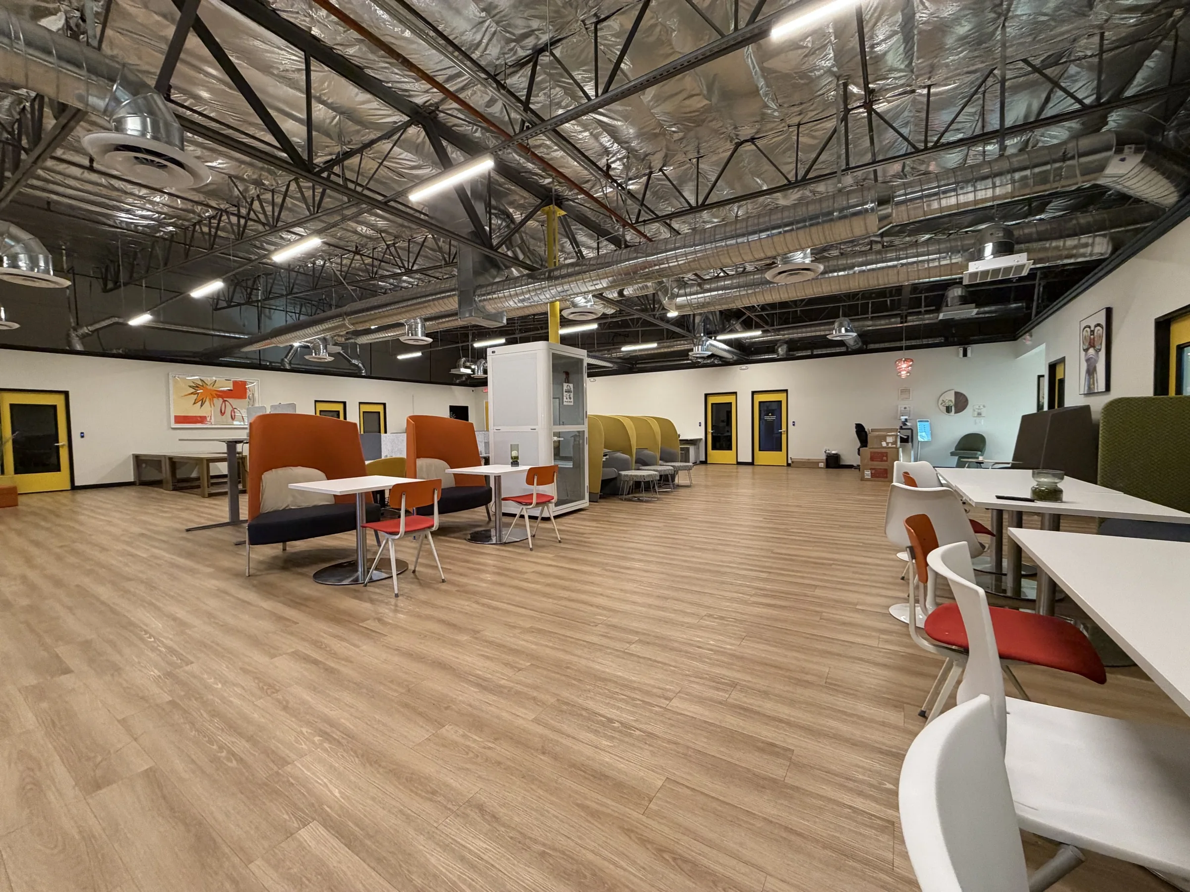 Open coworking floor at Muze Office Las Vegas with shared desks, lounge seating, and private work booths